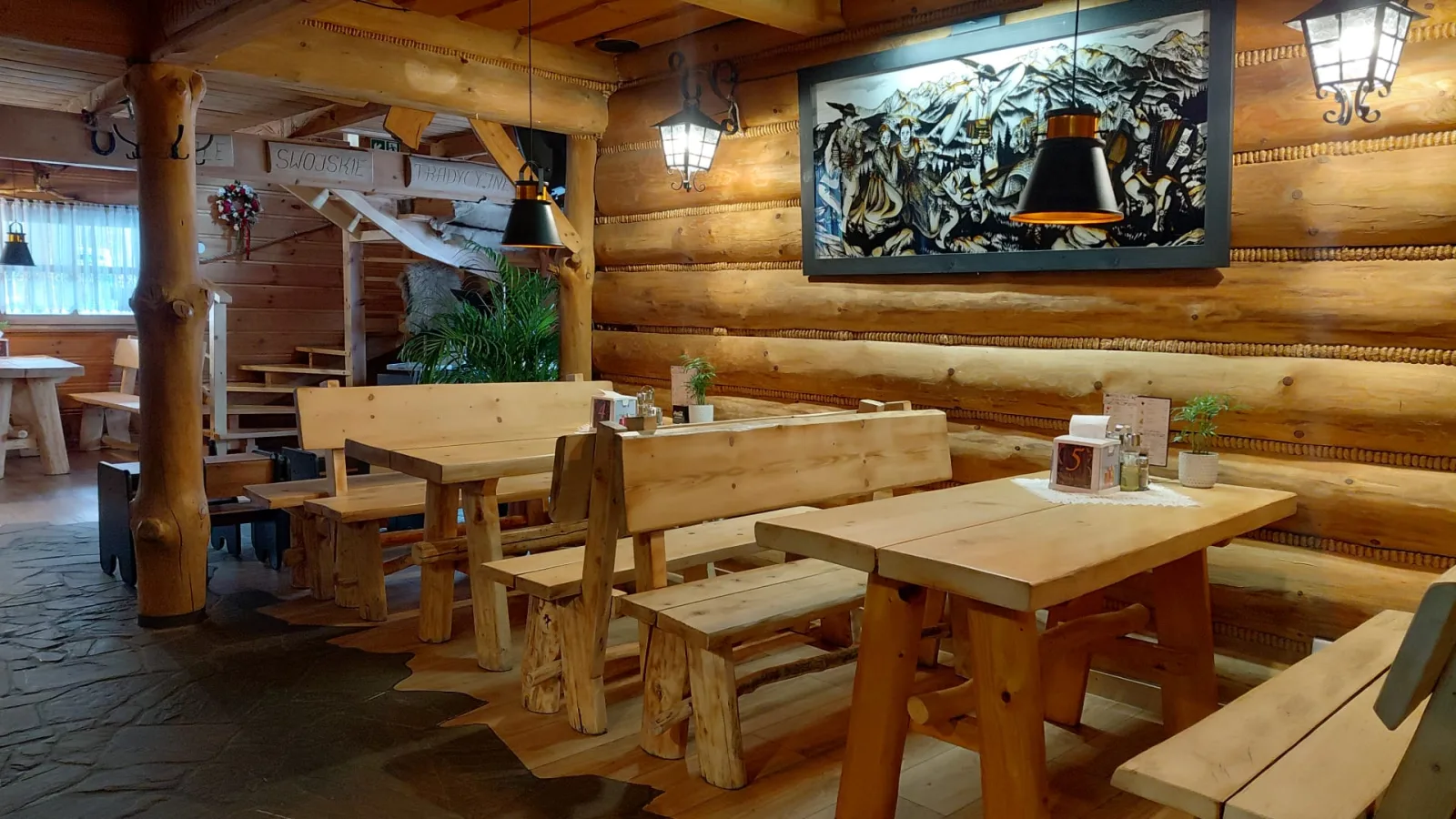 Drewniane wnętrze restauracji Sielska Chata w Rabce-Zdroju — sala z bali z dębowymi ławami